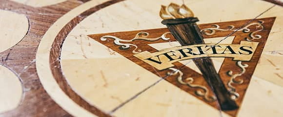 Image of the Veritas logo- a torch in front of a triangle with the word Veritas overlaid in front